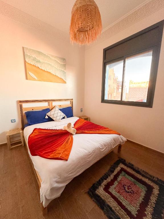 a bedroom with a bed and a large window at Blue Pearl Surf & Yoga House in Tamraght Ou Fella