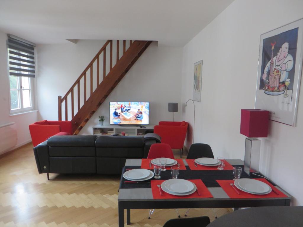 a living room with a black couch and red chairs at Au Quai Des Pecheurs in Strasbourg