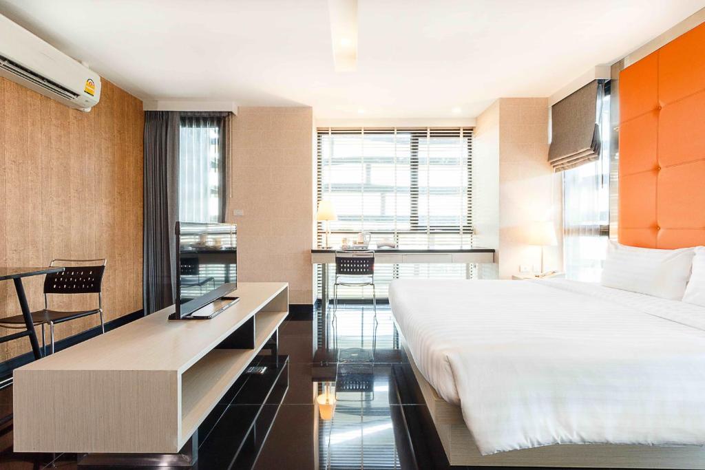 A wider bedroom view shows the bed, sitting area, desk, and television console together.