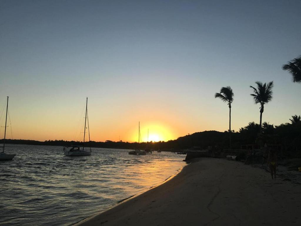 a sunset over a beach with boats in the water at Relax Private Room - Santo André, BA in Santo André