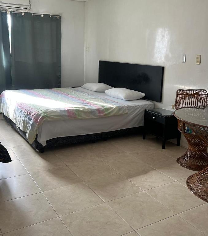 a bed with two pillows and a table in a room at Hotel Santa Barbara in Arauca