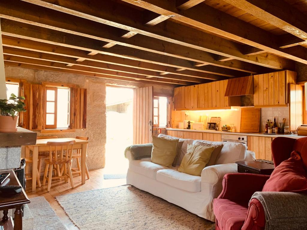 a living room with a white couch and a kitchen at Refúgio da Póvoa Dão in Silgueiros