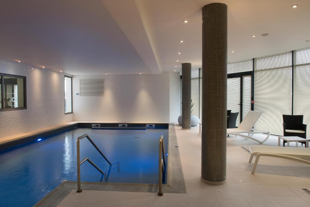 a swimming pool in a house with a table and chairs at Domitys - Le Carillon d'or in Maubeuge