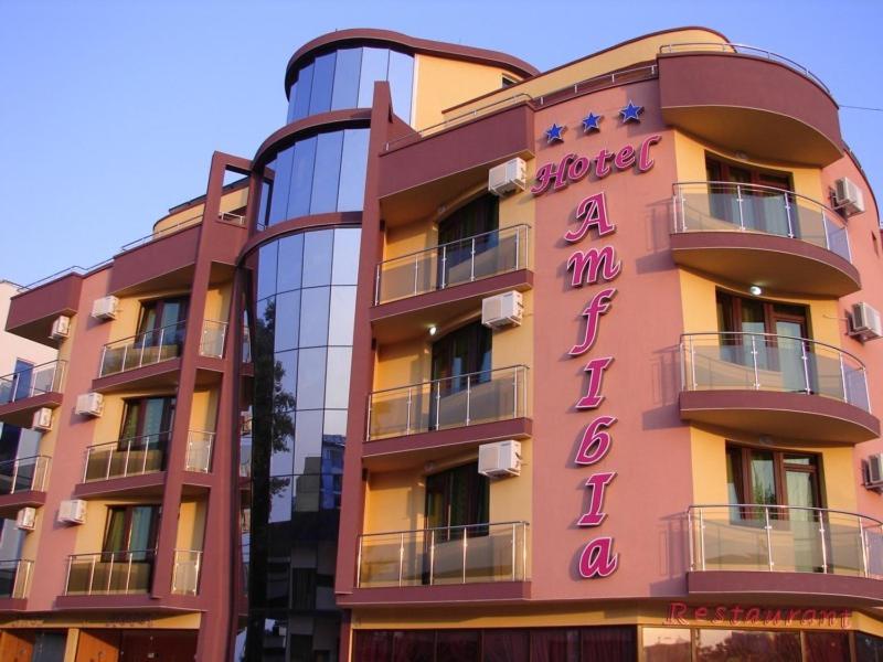 a pink building with a sign on it at Hotel Amfibia in Primorsko