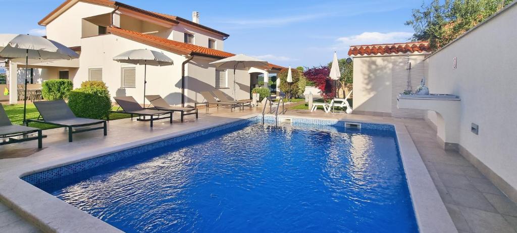 a swimming pool in a yard next to a house at Villa Kasandra - Ruhe & Eleganz in Buje, Istrien in Kaštel