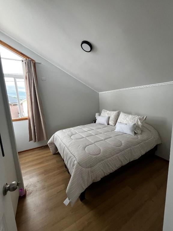 a white bedroom with a bed with pillows and a window at Casa Jesy in Frutillar