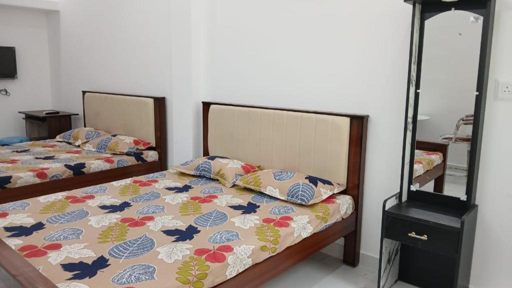 a bedroom with two beds and a mirror at Anand Lodge in Thiruchendur
