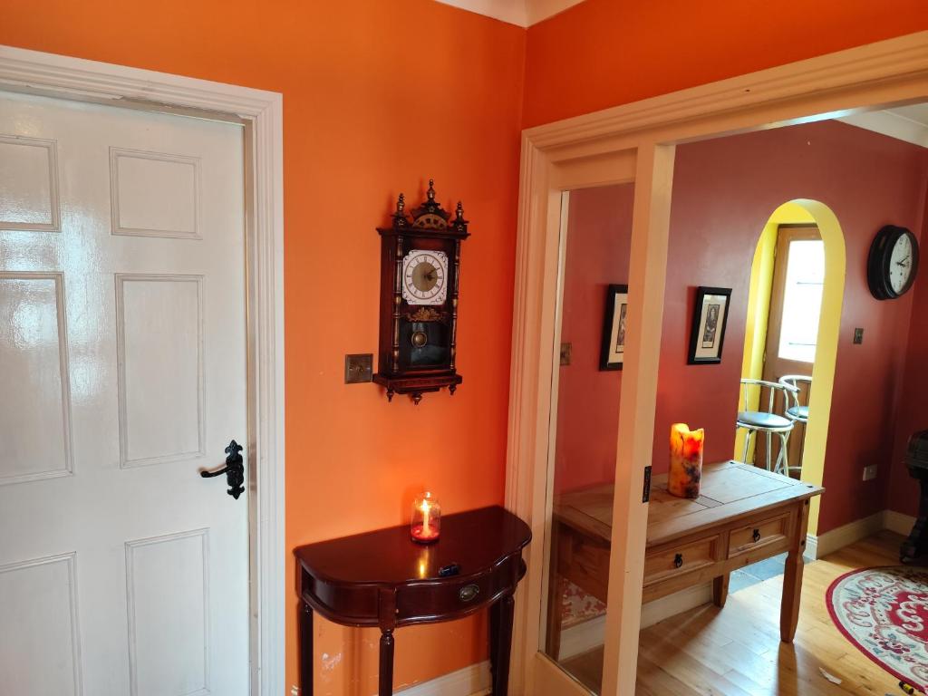 an orange room with a clock and a table with a candle at An Tuar Ceatha in Castlebar