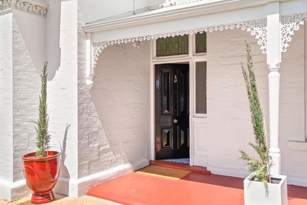 a front door of a white house with two potted plants at Belle Escapes - The Light House in Glenelg