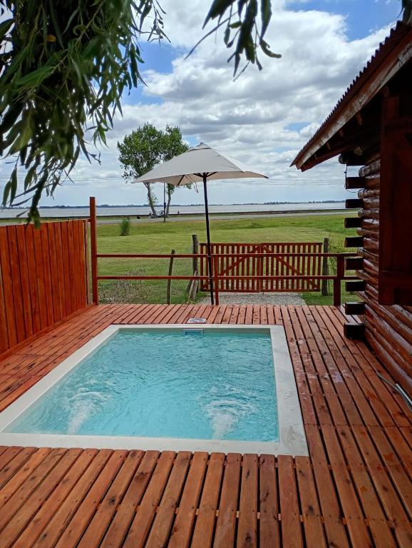 a swimming pool on a deck with an umbrella at Cabaña Puesta del sol in Chascomús