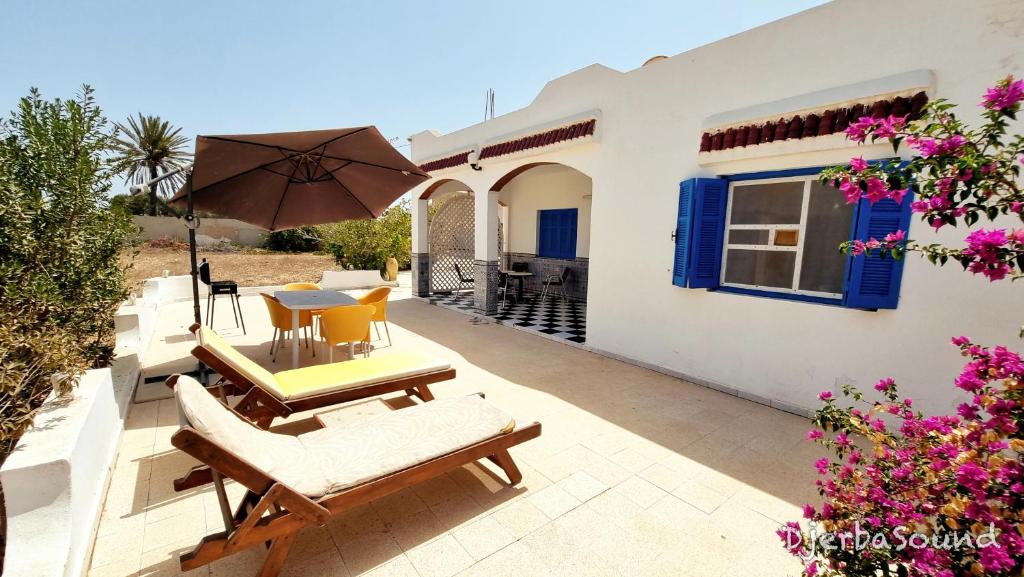 a patio with a table and chairs and an umbrella at Villas calme et sans vis-à-vis proche de la plage Tezdaine in Midoun