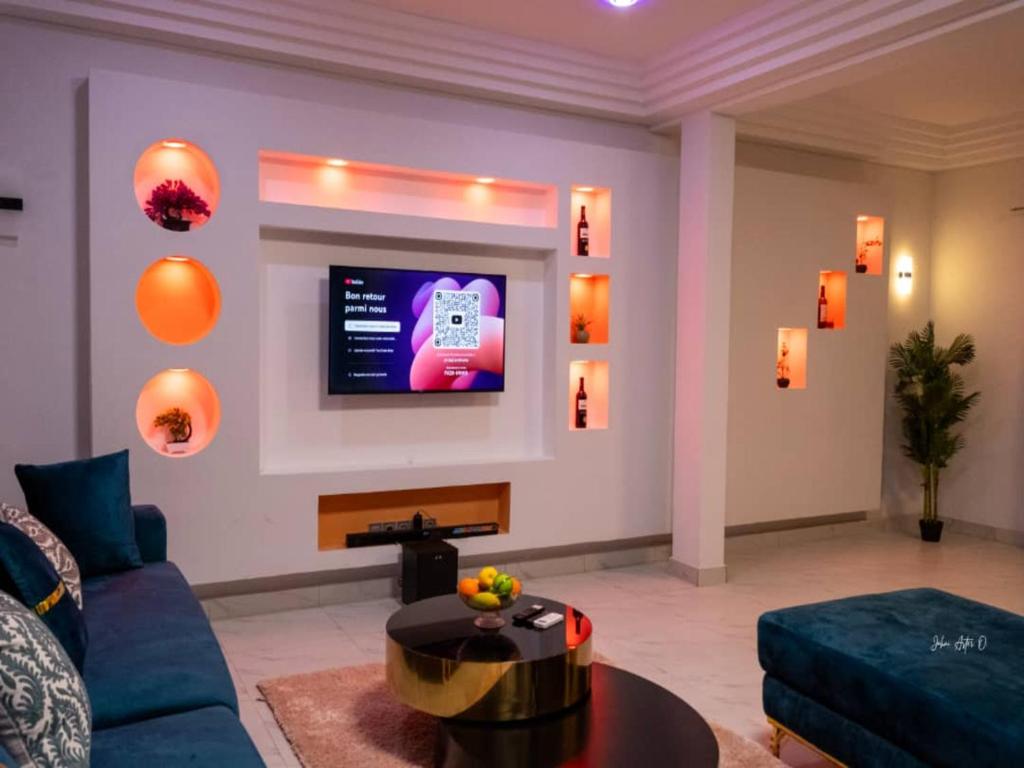 een woonkamer met een bank en een tv aan de muur bij Maison Recla in Lomé