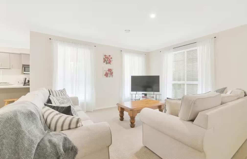 a white living room with white furniture and a television at Prime on Piper in Bathurst