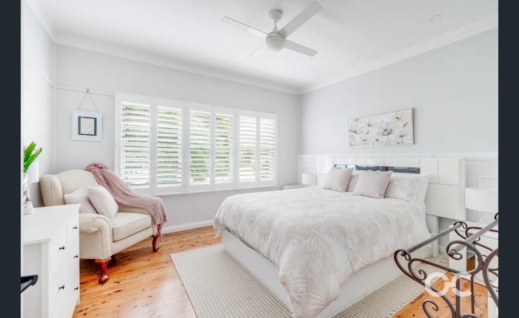 a white bedroom with a bed and a chair at Wollemi Cottage Orange in Orange