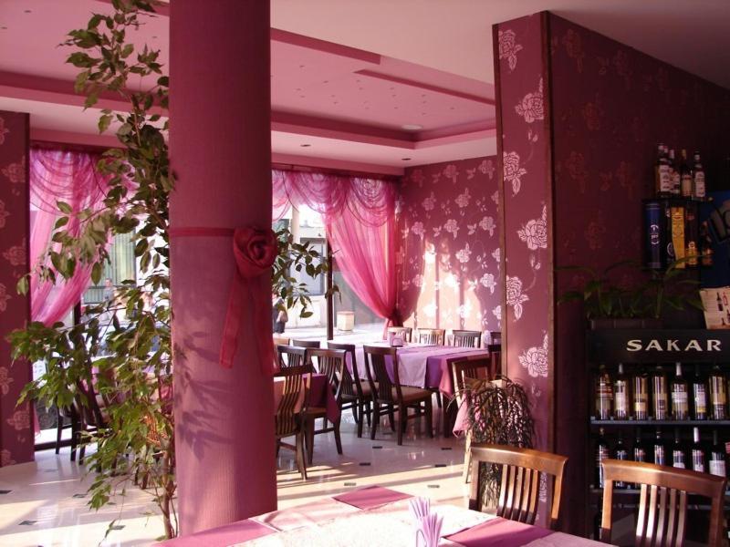 un ristorante con pareti e tavoli rosa e sedie di Hotel Amfibia a Primorsko