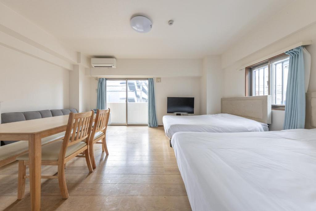 a hotel room with two beds and a table and chairs at Jintai House201 in Fukuoka