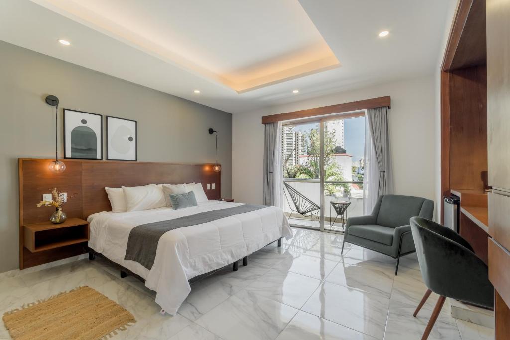 a bedroom with a bed and a chair and a window at CASA LIMA- Executive Design Suites in Cancún