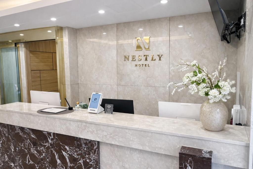 a reception desk in a lobby with a vase of flowers at Nestly Hotel in Busan