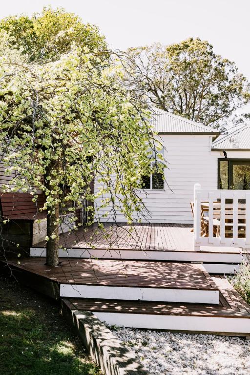 a house with a bench and a tree on a deck at Old Maffra Cottage in Maffra