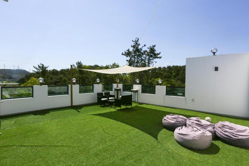 a patio with a table and chairs on the grass at Busan Mandiga Pool Villa in Busan