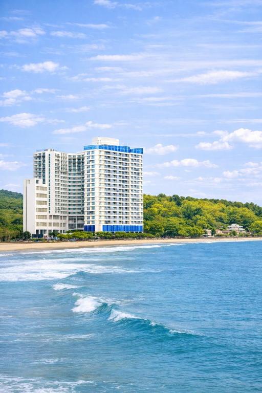 a large building on the beach next to the ocean at Yangyang Cohost Studio in Yangyang