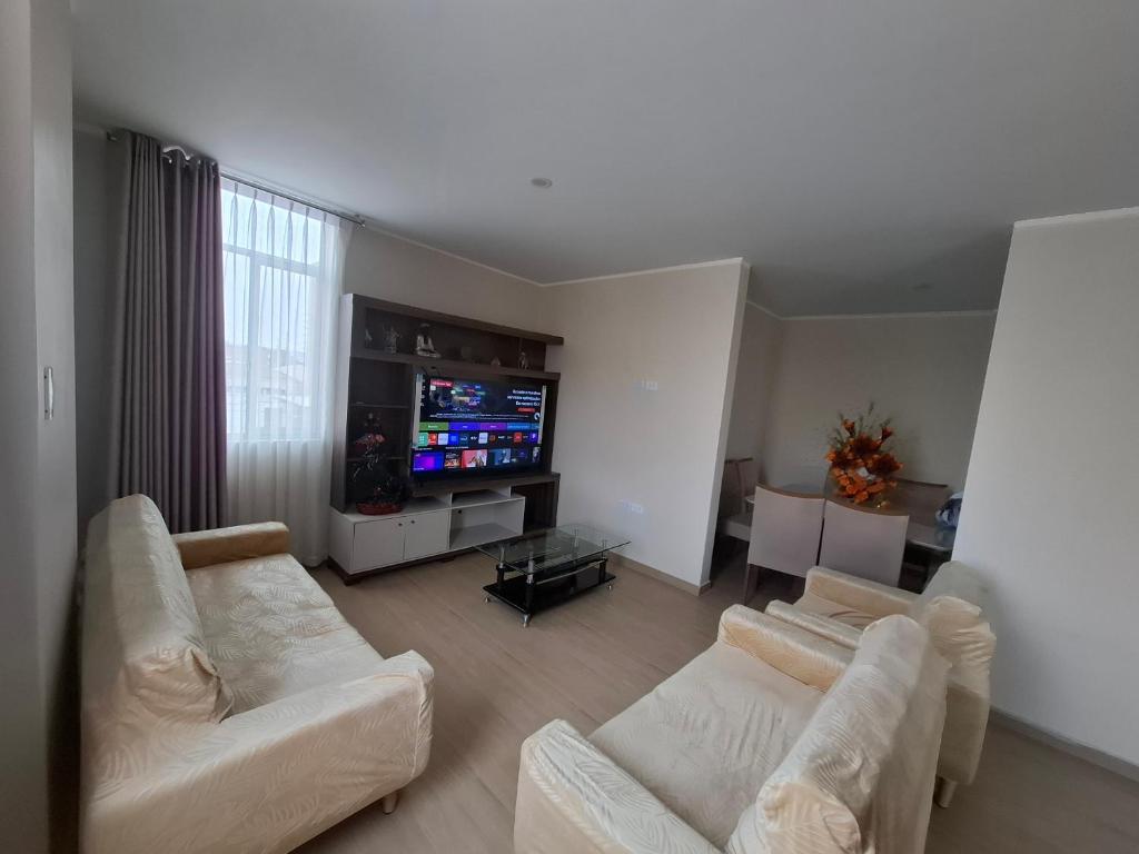 a living room with two white couches and a television at Miski Wasi in Tacna