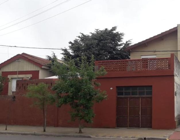 a red house with a garage and a tree in front at Cedro Azul in Monte Hermoso
