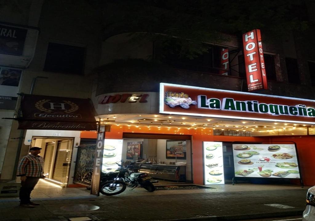 a man standing in front of a restaurant at night at Hotel Ejecutivo in Pereira