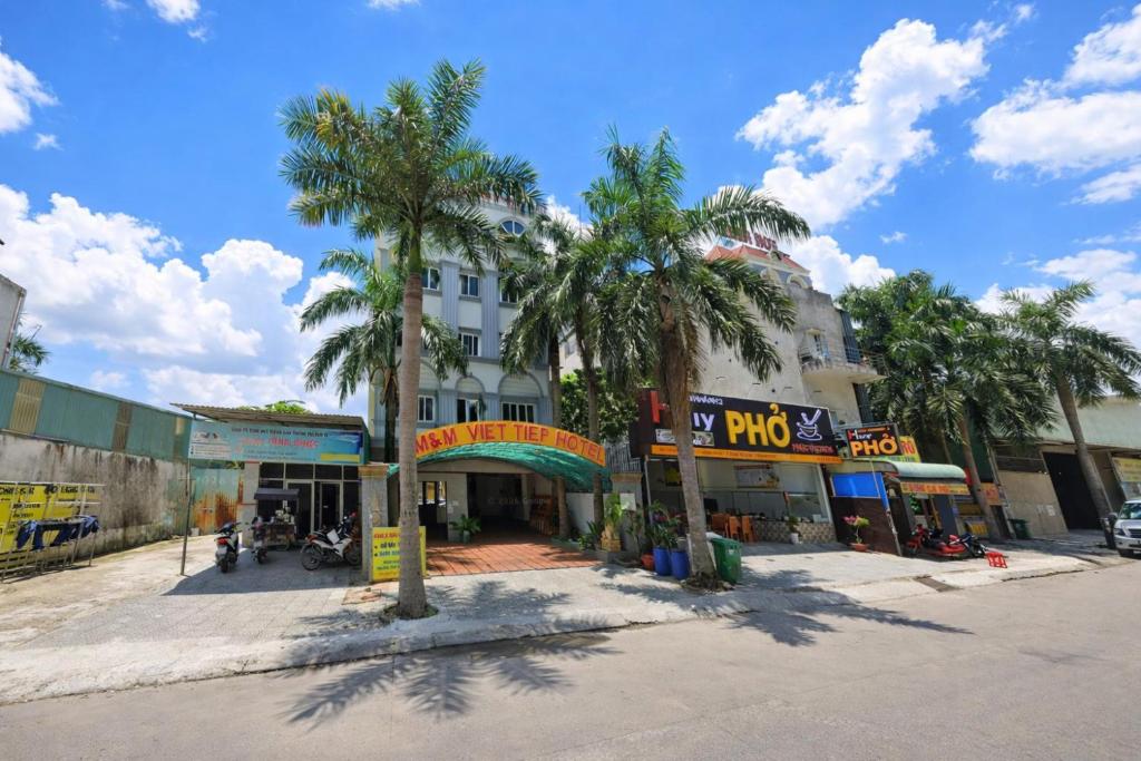a street with palm trees in front of a building at M&M Việt Tiệp Hotel in Dĩ An