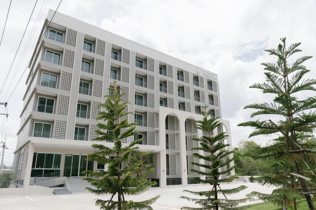 a white building with trees in front of it at M Hotel Kanchanaburi in Ban Chuk Kum