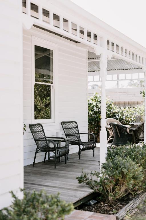 a white house with two chairs and a table on a porch at Oakview Country House Maffra in Maffra
