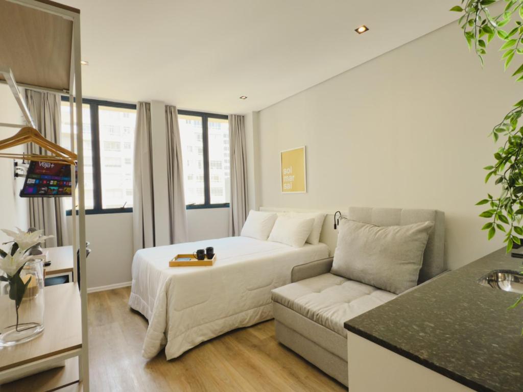 a living room with a white bed and a couch at Apê Smart Santos - Praia do Gonzaga in Santos
