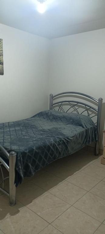 a bed with a blue comforter in a room at Agradable habitación C in Mexicali