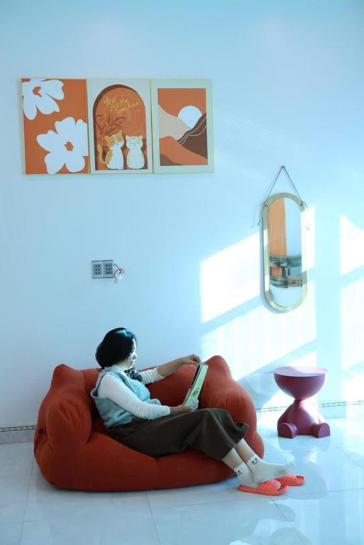 a woman sitting on a red couch in a room at Mocha Vila Mộc Châu in Mộc Châu