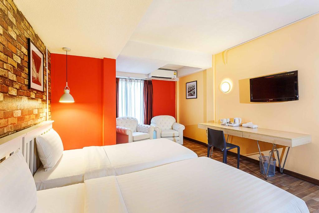 A colorful room pairs two beds with a wall-mounted television, desk and seating area.