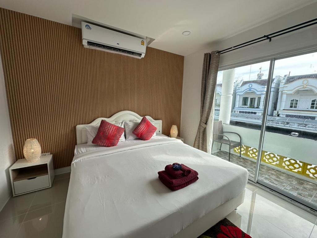 a bedroom with a white bed with red pillows and a window at Inn Dulgence in Patong Beach