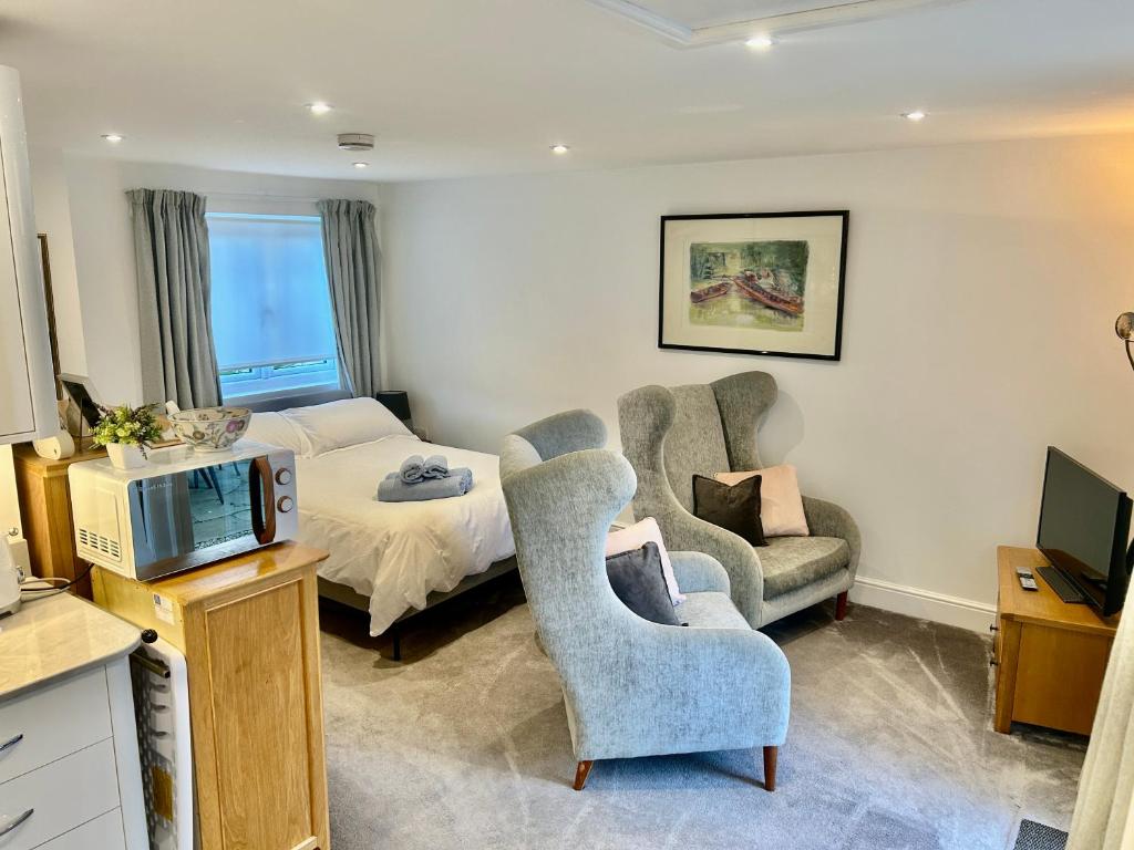 a bedroom with a bed and a tv and a chair at Cotswold studio with kitchen & patio in Witney