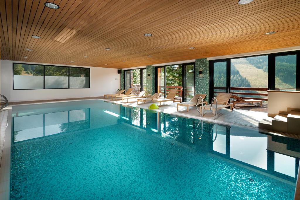 a swimming pool in a house with windows at Hotel Adam in Špindlerův Mlýn