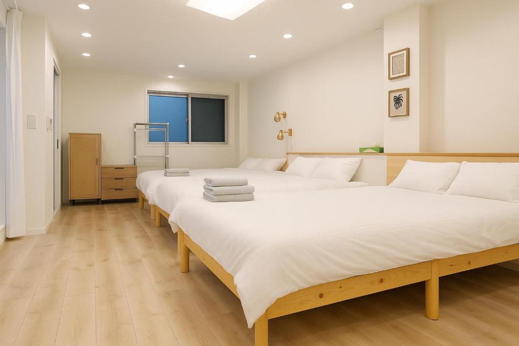 a bedroom with two large beds with white sheets at 旅館ほのか in Osaka
