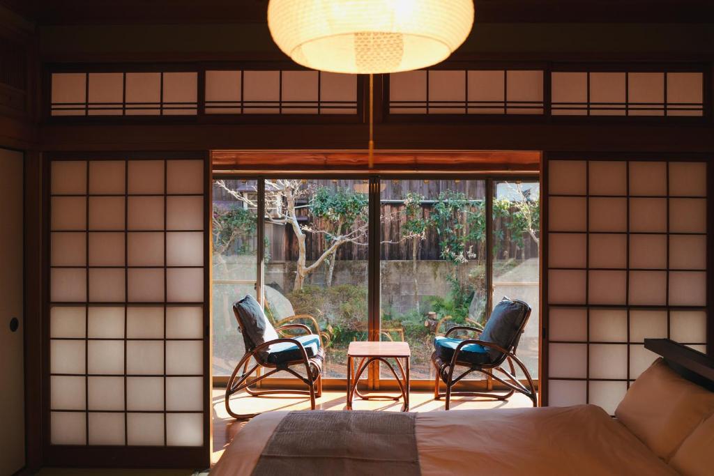 a bedroom with a bed and chairs on a patio at アリュール照波園 in Beppu