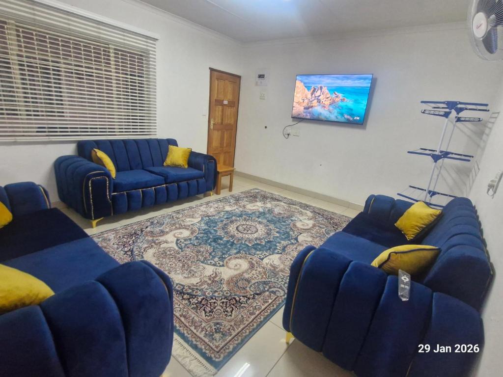 a living room with two blue couches and a rug at Royal Inn - Fully Furnished Self-Catering Apartments in Lenasia