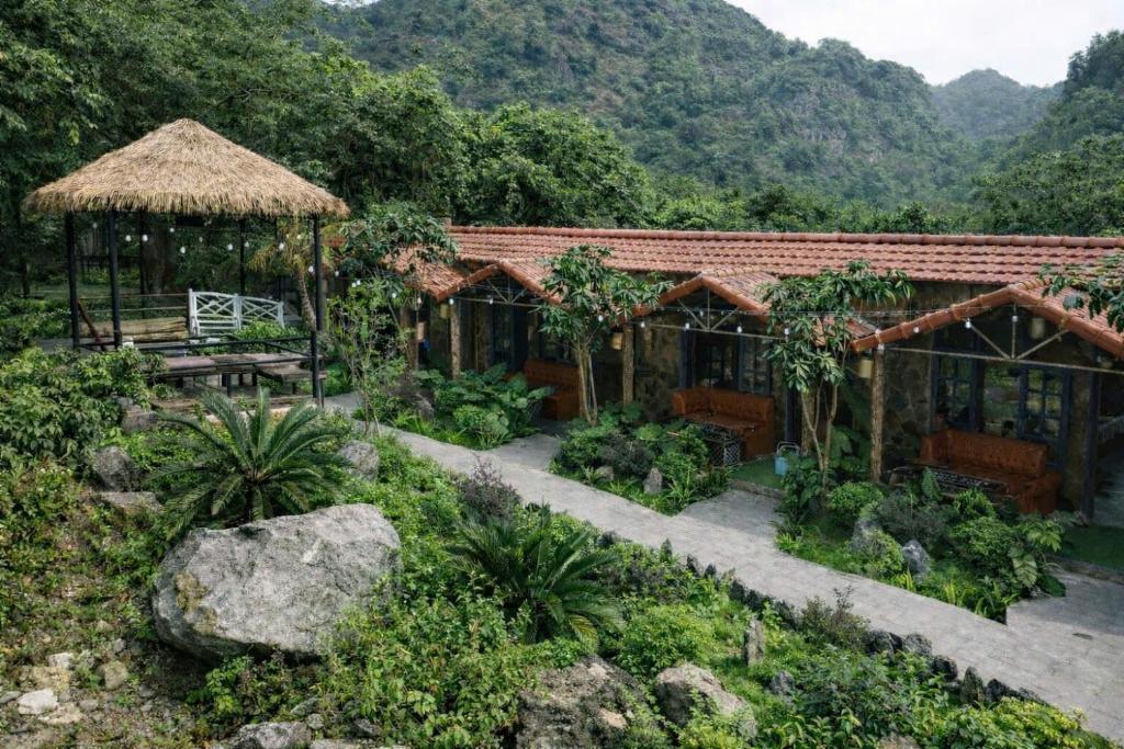 a house with a garden in front of a mountain at Trang An Mountain River Ecolodge in Ninh Binh