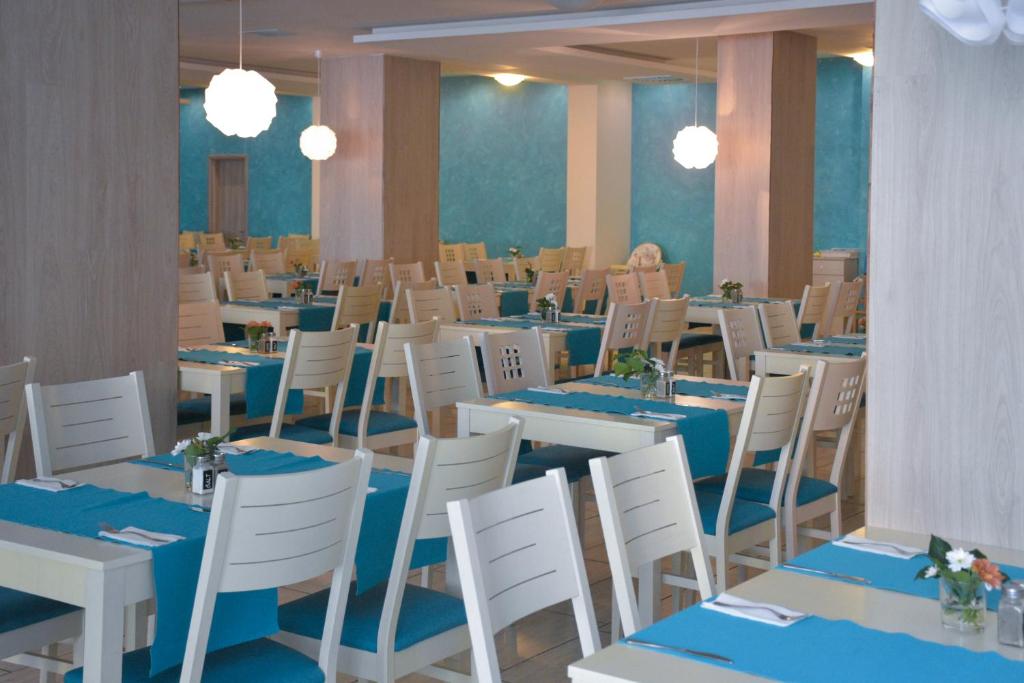 a dining room with tables and white chairs with blue linens at Arena Mar Hotel and SPA in Golden Sands