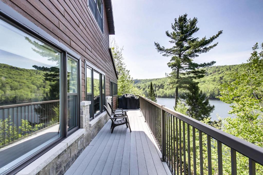 a balcony with a bench and a view of a lake at Lakefront - Chalet Le Missionnaire in Trois Rives