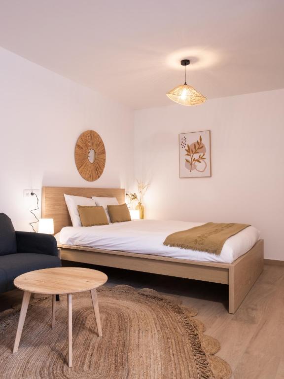 a bedroom with a large bed and a table at Studio chic proche aéroport et centre-ville in Charleroi
