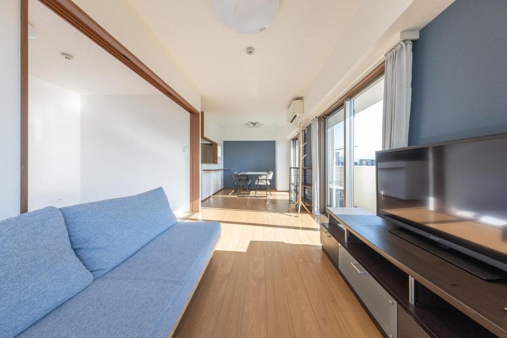 a living room with a blue couch and a television at Jintai House601 in Shiobaru