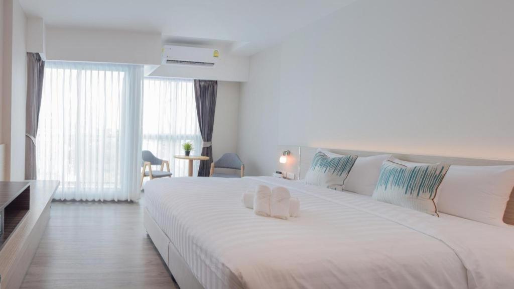 a white bedroom with a large white bed with pillows at Analynn Hotel in Ban Kohong