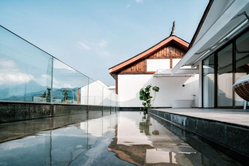 an external view of a house with a reflecting pool at Xianzai Houshe Boutique Hotel in Dujiangyan