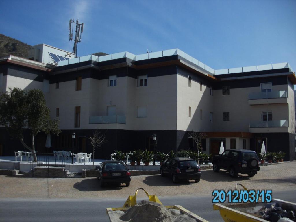 ein großes Gebäude mit Autos auf einem Parkplatz in der Unterkunft Hotel La Duquesa in Pinos Genil