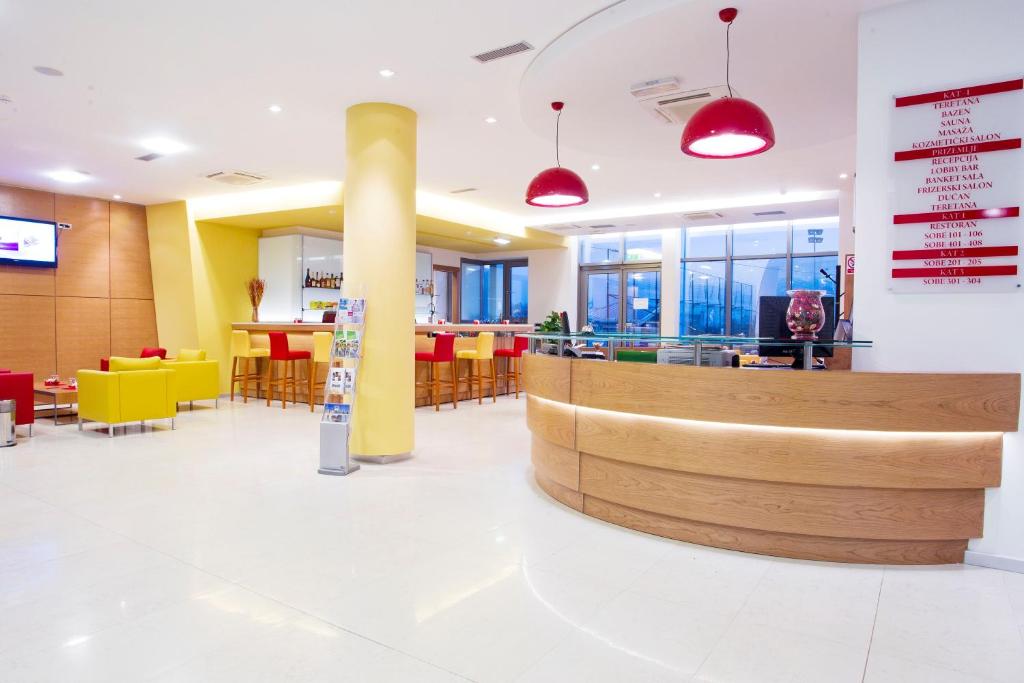 a lobby of a restaurant with yellow and red chairs at Hotel Sport in Ivanić-Grad